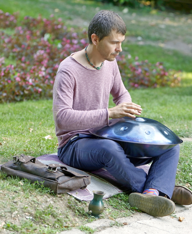 15 - A person playing a handpan, a modern musical instrument known for its calming, resonant tones